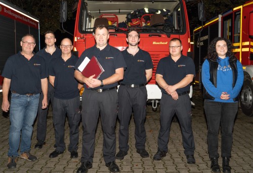fünf Feuerwehrleute und Kommandant Liehr im Dunkeln vor einem Feuerwehrfahrzeug       