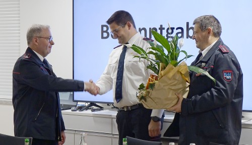 Axel Faulhaber schüttelt die Hand von Stefan Hetzel. Jürgen Britz hält einen Blumenstrauß.