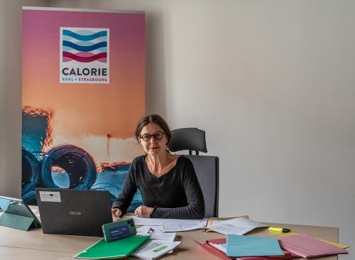 Generaldirektorin an ihrem Schreibtisch, dahinter das Rollup mit dem Calorie-Logo            