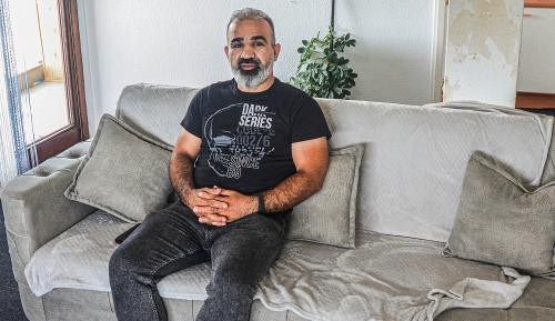 Der geflüchtete irakische Kurde Nawzad Mohammad sitzt auf dem heimischen Sofa.