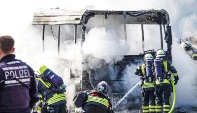 Feuerwehrkräfte löschen einen brennenden Linienbus
