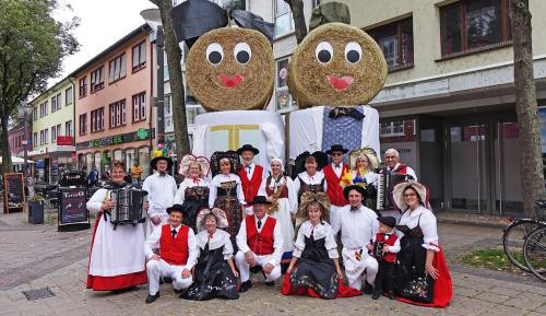 HanauerLandMarkt 2025 Eine Trachtengruppe posiert vor den Strohpuppen in der Innenstadt