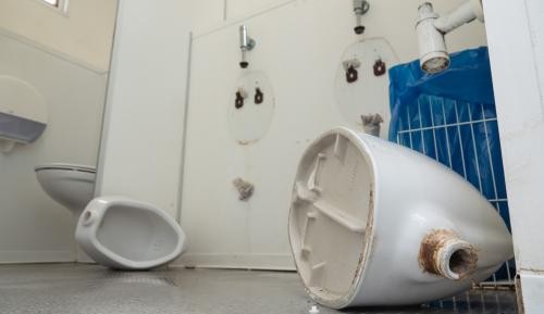 Auf dem Toilettenboden liegen zwei abgerissene Urinale.