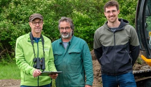 Oliver Schmiedle, Jürgen Luhr und Michael Faller stehen vor einem Schaufelbagger.
