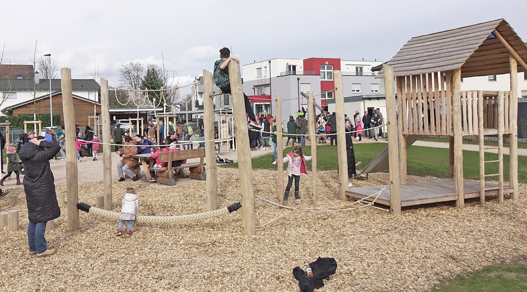 Kinder spielen unter Aufsicht ihrer Eltern auf einem neuen Spielplatz.
