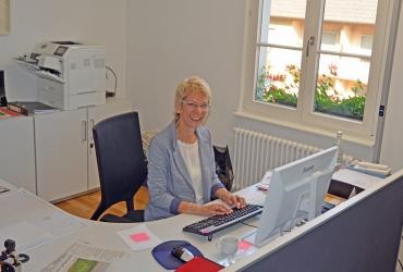 Eine Frau sitzt an einem Schreibtisch vor einem Computer.