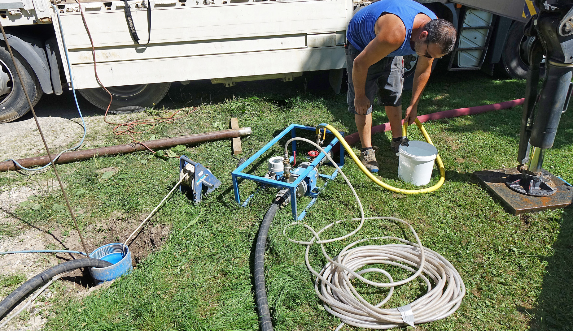 Ein Mann leitet mit einem gelben Schlauch Wasser in einen weißen Eimer.