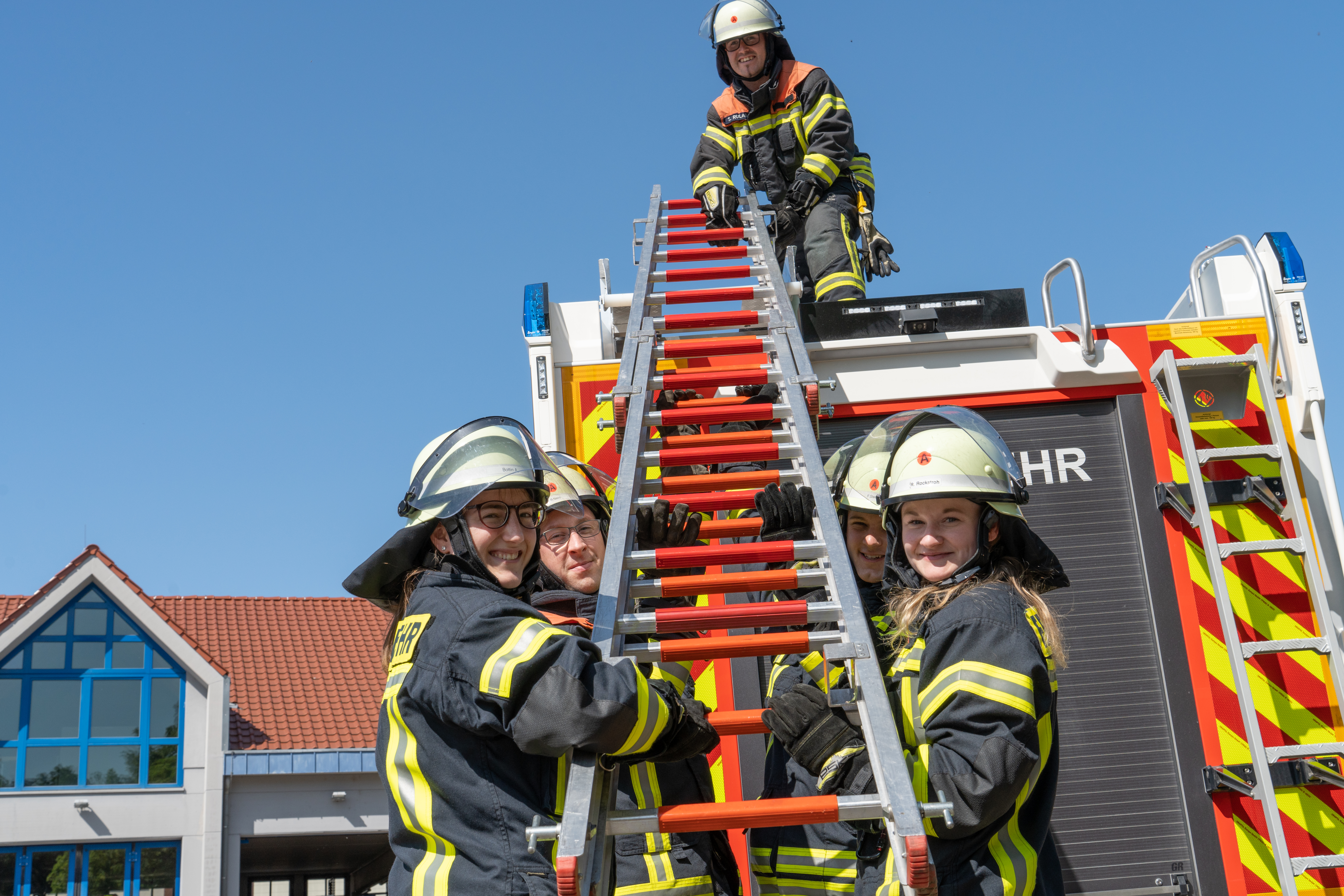 Feuerwehr-Einsatzkräfte holen eine Leiter von einem Feuerwehrfahrzeug.