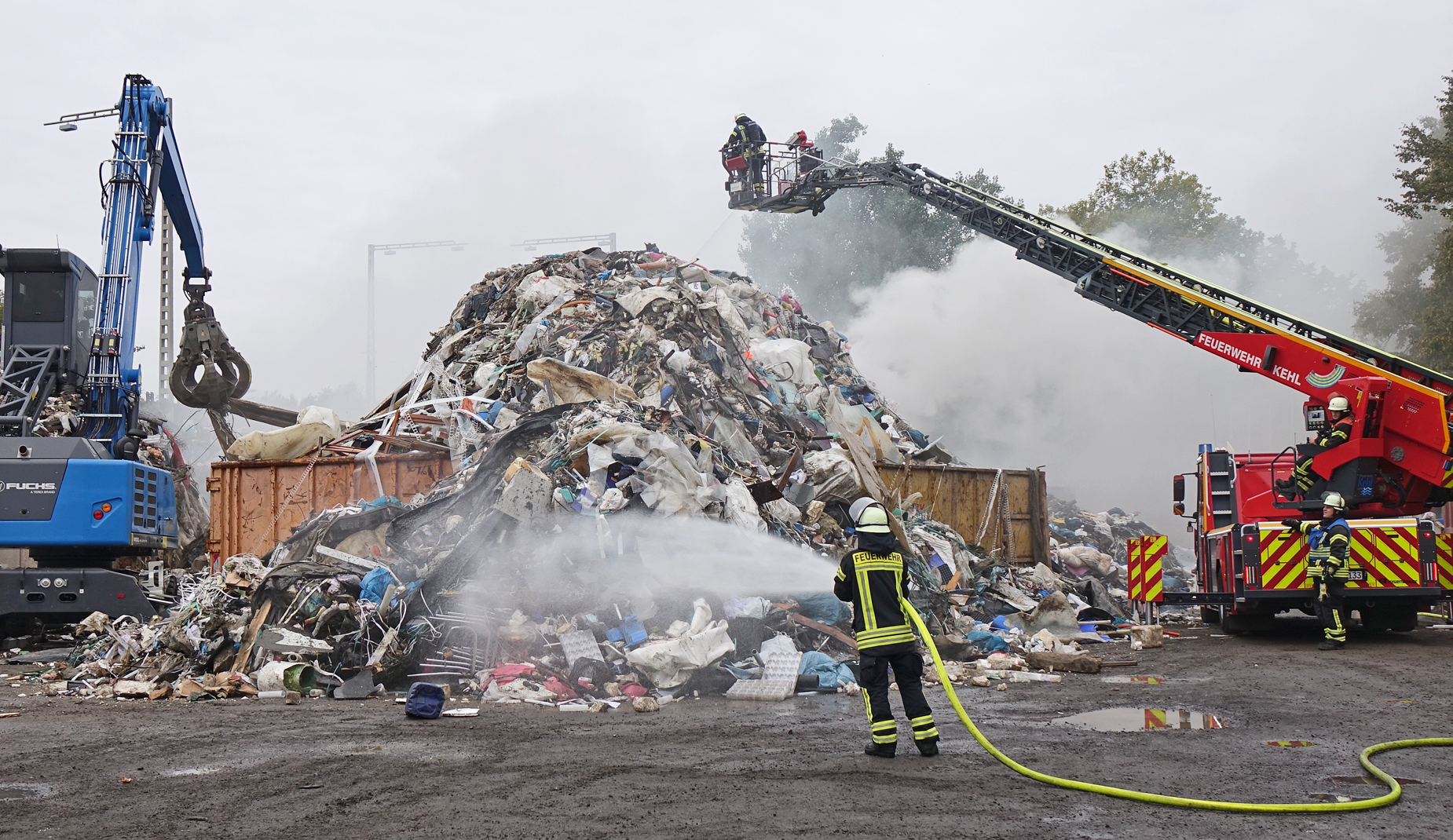 Die Feuerwehr löscht einen qualmenden Müllberg